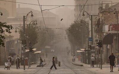 Des gens traversant les voies du tramway sur la rue Jaffa, à Jérusalem lors d'une journée estivale brumeuse, le 11 août 2025. (Crédit : Chaïm Goldberg/Flash90)