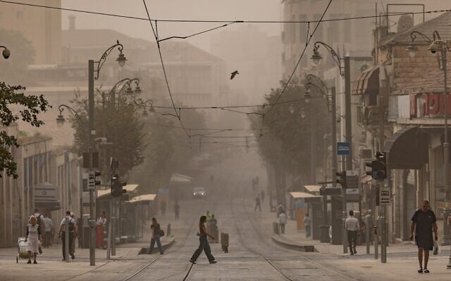 Des gens traversant les voies du tramway sur la rue Jaffa, à Jérusalem lors d'une journée estivale brumeuse, le 11 août 2025. (Crédit : Chaïm Goldberg/Flash90)