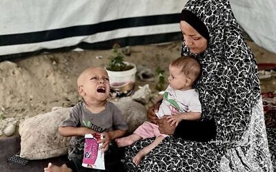Abdulla Abu Zarka (à gauche), un enfant qui souffrirait de malnutrition à Gaza, avec sa mère et son frère, sur une photo diffusée en ligne en juillet 2025. (Crédit : X ; utilisé conformément à la clause 27a de la loi sur le droit d'auteur)
