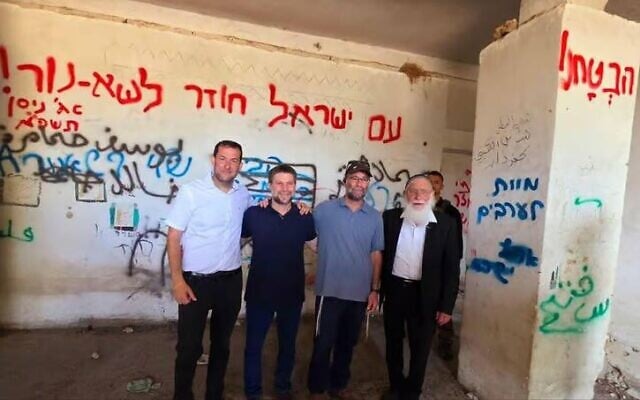 Le ministre Bezalel Smotrich (2ᵉ depuis la gauche) photographié devant un mur couvert de graffitis, dont l’un proclamant “Mort aux Arabes”. À sa gauche : Yossi Dagan, chef du Conseil régional de Samarie, à Sa-Nur, le 6 août 2025.
(Crédit : Capture d'écran/X/Roi Hadi / Conseil régional de Samarie; utilisée conformément à la clause 27a de la loi sur le droit d'auteur)