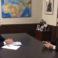 Le Premier ministre Benjamin Netanyahu regardant une amulette représentant « une carte de la Terre promise », qui lui a été offerte par son intervieweur, le 12 août 2025. (Crédit : Capture d'écran/i24 news)