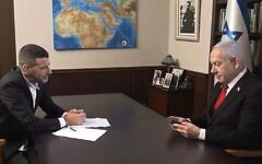 Le Premier ministre Benjamin Netanyahu regardant une amulette représentant « une carte de la Terre promise », qui lui a été offerte par son intervieweur, le 12 août 2025. (Crédit : Capture d'écran/i24 news)