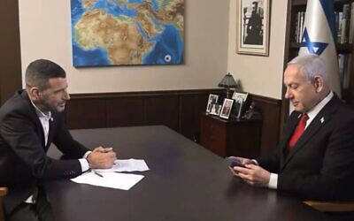 Le Premier ministre Benjamin Netanyahu regardant une amulette représentant « une carte de la Terre promise », qui lui a été offerte par son intervieweur, le 12 août 2025. (Crédit : Capture d'écran/i24 news)