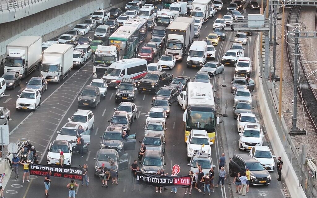 Les familles des otages et des manifestants bloquant l'autoroute Ayalon à Tel Aviv au début d'une journée de manifestations à travers Israël pour réclamer la libération des otages et la fin de la guerre à Gaza, le 26 août 2025. (Crédit : Zvulun Ziskiend/Mouvement de protestation pour la démocratie)