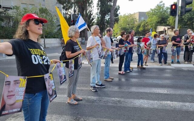 Des manifestants bloquant le passage piéton devant le domicile du ministre de l'Économie, Nir Barkat, à Jérusalem, le 26 août 2025. (Crédit : Mouvement de protestation pour la démocratie)