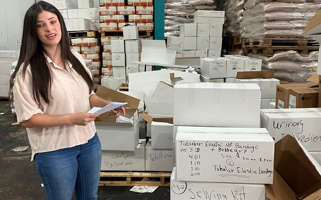 Najwa Mulla, une bénévole, se tient dans un entrepôt du village druze de Julis, en Galilée, à côté de cartons de fournitures médicales qui seront envoyés à des hôpitaux de Soueïda, en Syrie, le 6 août 2025. (Crédit : Diana Bletter/Times of Israel)