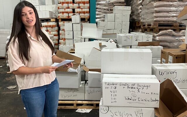 Najwa Mulla, une bénévole, se tient dans un entrepôt du village druze de Julis, en Galilée, à côté de cartons de fournitures médicales qui seront envoyés à des hôpitaux de Soueïda, en Syrie, le 6 août 2025. (Crédit : Diana Bletter/Times of Israel)