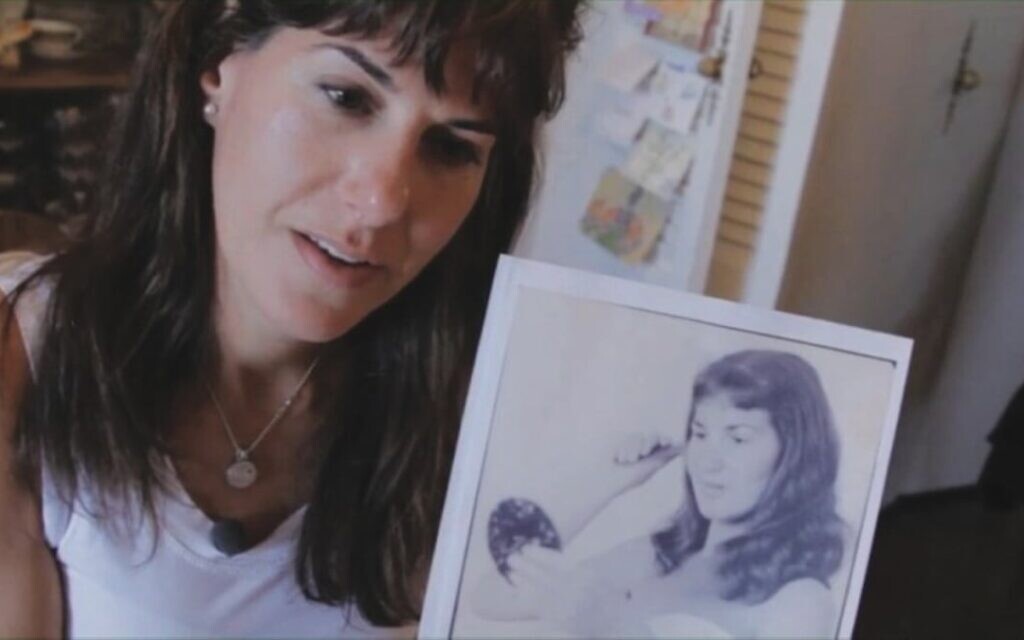 La réalisatrice Marisa Fox tenant une photo de sa mère, Tamar Fromer-Fox (alias Hela Hocherman), dans une scène de « My Underground Mother ». (Crédit : Andrew Abrahams)
