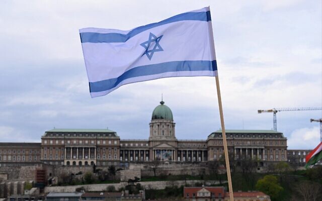 Illustration : Un drapeau israélien est hissé sur le pont Széchenyi, avec le château de Buda à Budapest en arrière-plan, le 2 avril 2025. (Crédit: Attila KISBENEDEK / AFP)