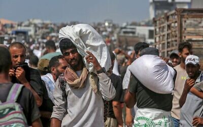 Des Palestiniens déplacés transportent des colis alimentaires alors que d'autres pillent des camions chargés d'aide humanitaire, à Khan Younès, dans le sud de la bande de Gaza, le 9 août 2025. (Crédit : AFP) Des Palestiniens déplacés transportent des colis alimentaires alors que d'autres pillent des camions chargés d'aide humanitaire, à Khan Younès, dans le sud de la bande de Gaza, le 9 août 2025. (Crédit : AFP)