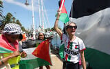 Des activistes brandissant des drapeaux "palestiniens" avant d'embarquer sur leurs bateaux pour rejoindre une flottille civile à destination de Gaza, dans le but de briser les restrictions maritimes strictes imposées par Israël sur Gaza et d'acheminer de l'aide humanitaire, à Barcelone, en Espagne, le 31 août 2025. (Crédit : Lluis Gene/AFP)