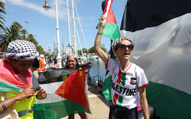 Des activistes brandissant des drapeaux "palestiniens" avant d'embarquer sur leurs bateaux pour rejoindre une flottille civile à destination de Gaza, dans le but de briser les restrictions maritimes strictes imposées par Israël sur Gaza et d'acheminer de l'aide humanitaire, à Barcelone, en Espagne, le 31 août 2025. (Crédit : Lluis Gene/AFP)