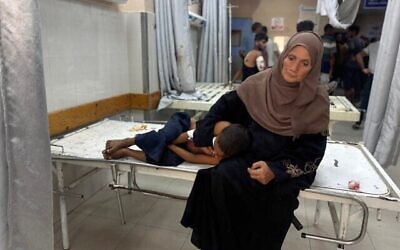 Une Gazaouie réconfortant un enfant, à l'hôpital Nasser, à Khan Younès, le 31 août 2025. (Crédit : AFP)