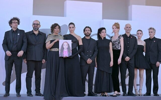 De gauche à droite : Le producteur tunisien Nadim Cheikhrouha, l'acteur israélien Amer Hlehel, la réalisatrice tunisienne Kaouther Ben Hania, l'actrice Saja Kilani, l'acteur Motaz Malhees, l'actrice Clara Khoury, la productrice Odessa Rae, Jim Wilson, l'actrice américaine Rooney Mara et l'acteur américain Joaquin Phoenix posent avec un portrait de la défunte Palestinienne Hind Rajab lors du tapis rouge du film "La voix de Hind Rajab", présenté en compétition à la 82ᵉ Mostra de Venise, au Lido, le 3 septembre 2025. (Crédit : Tiziana Fabi/AFP)