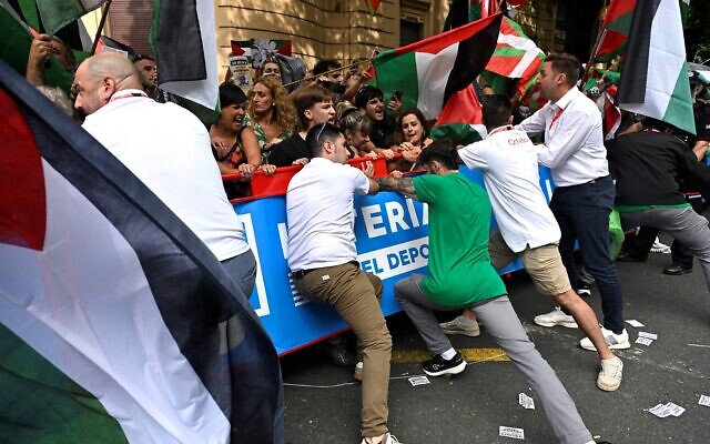 Les membres du personnel de la Vuelta tiennent des barrières tandis que des manifestants anti-Israël brandissant des drapeaux "palestiniens" et basques manifestent lors de la onzième étape du tour cycliste Vuelta a España, une course de 167 km entre Bilbao et Bilbao, le 3 septembre 2025. (Crédit : Ander Gillenea/AFP) Les membres du personnel de la Vuelta tiennent des barrières tandis que des manifestants anti-Israël brandissant des drapeaux "palestiniens" et basques manifestent lors de la onzième étape du tour cycliste Vuelta a España, une course de 167 km entre Bilbao et Bilbao, le 3 septembre 2025. (Crédit : Ander Gillenea/AFP)