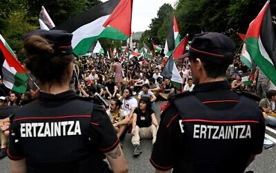 Des manifestants anti-Israël brandissant des drapeaux "palestiniens" et basques manifestent aux côtés d'agents de la police régionale basque, l'Ertzaintza, à l'issue de la 11ᵉ étape de la Vuelta cycliste, à Bilbao, le 3 septembre 2025. (Crédit : Ander Gillenea/AFP)