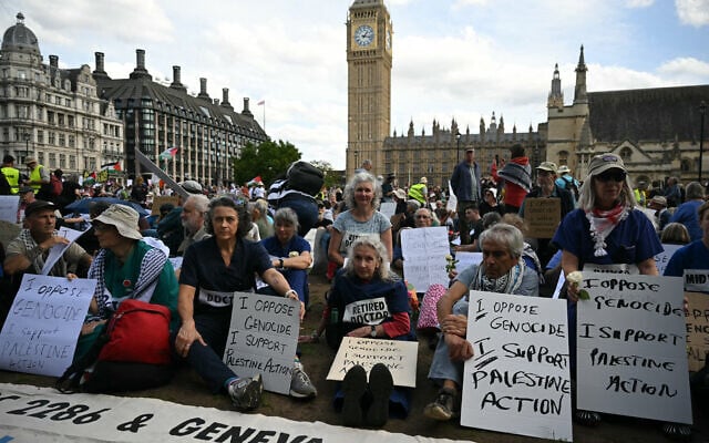 Des manifestants assis avec leurs pancartes en soutien au groupe terroriste Palestine Action, appelant à la levée de l'interdiction récemment imposée sur Parliament Square, dans le centre-ville de Londres, le 6 septembre 2025. (Crédit : Justin Tallis/AFP)