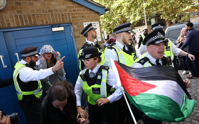 Des manifestants sont retenus par des policiers et des agents de sécurité alors qu'ils protestent devant l'entrée du salon Defence and Security Equipment International (DSEI) au centre ExCeL, dans l'est de Londres, le 9 septembre 2025. (Crédit : Toby Shepheard / AFP)