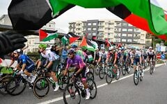 Des manifestants anti-israéliens et pro-palestiniens brandissent des drapeaux et crient alors que le peloton passe à Poio au début de la 16e étape de la Vuelta a Espana, le 9 septembre 2025. (Crédit : Miguel RIOPA / AFP)