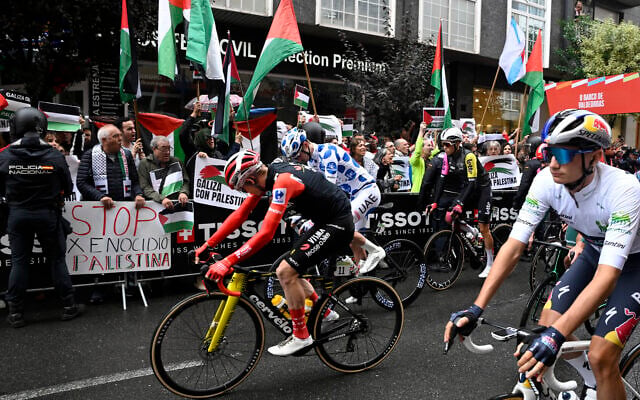Des manifestants pro-palestiniens brandissent des drapeaux palestiniens alors que les coureurs prennent le départ de la 17e étape de la Vuelta a Espana, une course de 143 km entre O Barco de Valdeorras et Alto de El Morredero, Ponferrada, le 10 septembre 2025. (Crédit : Miguel RIOPA / AFP)