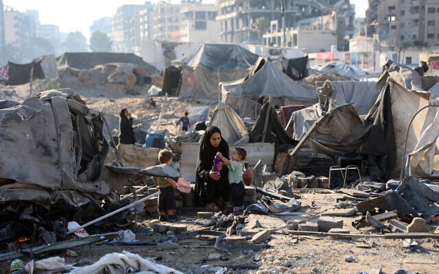Une Gazaouie déplacée assise avec des enfants au milieu de tentes dévastées, après que l'armée israélienne a frappé la nuit précédente un bâtiment et endommagé les abris temporaires environnants, dans le quartier de Rimal, à Gaza-City, le 13 septembre 2025. (Crédit : Omar al-Qattaa/AFP) Une Gazaouie déplacée assise avec des enfants au milieu de tentes dévastées, après que l'armée israélienne a frappé la nuit précédente un bâtiment et endommagé les abris temporaires environnants, dans le quartier de Rimal, à Gaza-City, le 13 septembre 2025. (Crédit : Omar al-Qattaa/AFP)