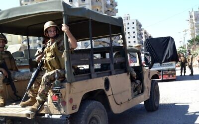 Des soldats libanais escortent un camion chargé d'armes qui quitte le camp de réfugiés palestiniens de Beddawi, près de la ville de Tripoli, dans le nord du pays, le 13 septembre 2025. (Crédit : Fathi AL-MASRI / AFP)
