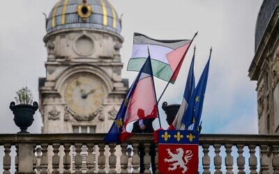 Un employé hissant le drapeau palestinien à côté du drapeau français, du drapeau de Lyon et du drapeau de l'Union européenne, au-dessus de l'entrée de l'hôtel de ville de Lyon, le jour où la France a reconnu l'État palestinien aux Nations unies, le 22 septembre 2025. (Crédit : Olivier Chassignole/AFP)
