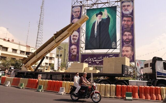 Un homme passant à moto devant un missile balistique Kheibar Shekan désactivé, devant une photo du guide suprême iranien, l'ayatollah Ali Khamenei, sur la place Bahrestan, à Téhéran, le 27 septembre 2025. (Crédit : Atta Kenare/AFP) Un homme passant à moto devant un missile balistique Kheibar Shekan désactivé, devant une photo du guide suprême iranien, l'ayatollah Ali Khamenei, sur la place Bahrestan, à Téhéran, le 27 septembre 2025. (Crédit : Atta Kenare/AFP)