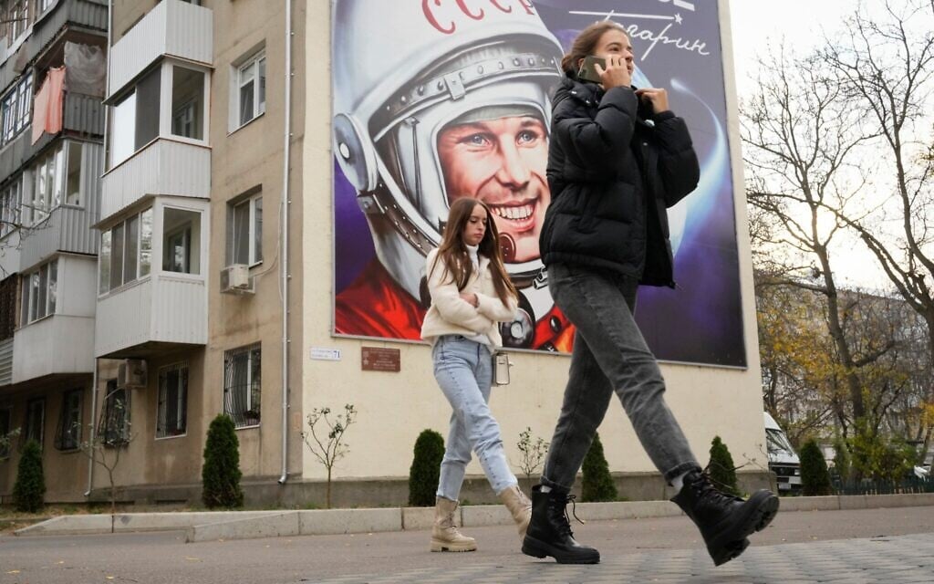 Illustration : Des passants devant un panneau publicitaire représentant le premier cosmonaute Youri Gagarine à Tiraspol, capitale de la région séparatiste de Transnistrie soutenue par la Russie, en Moldavie, le 1ᵉʳ Novembre 2021. (Crédit : Dmitri Lovetsky/AP Photo) Illustration : Des passants devant un panneau publicitaire représentant le premier cosmonaute Youri Gagarine à Tiraspol, capitale de la région séparatiste de Transnistrie soutenue par la Russie, en Moldavie, le 1ᵉʳ Novembre 2021. (Crédit : Dmitri Lovetsky/AP Photo)