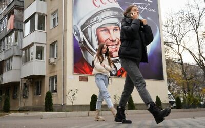 Illustration : Des passants devant un panneau publicitaire représentant le premier cosmonaute Youri Gagarine à Tiraspol, capitale de la région séparatiste de Transnistrie soutenue par la Russie, en Moldavie, le 1ᵉʳ Novembre 2021. (Crédit : Dmitri Lovetsky/AP Photo)