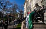 Des étudiants manifestent contre la guerre à Gaza, et des passants déambulent dans Harvard Yard, non loin de la statue de John Harvard, le premier bienfaiteur du Harvard College, drapé dans le drapeau palestinien, lors d'un campement de l'Université Harvard à Cambridge, dans le Massachusetts, le 25 avril 2024. (Crédit : AP Photo/Ben Curtis)