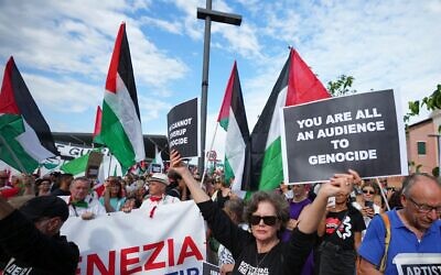 Un manifestant brandissant une pancarte « Vous êtes tous complices du génocide » lors d’une marche de soutien aux Palestiniens de Gaza, pendant le Festival du film de Venise, en Italie, le 30 août 2025. (Crédit : Alessandra Tarantino/Invision/AP)