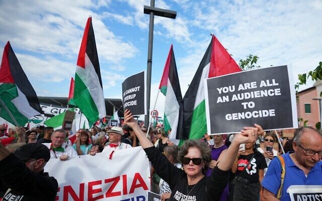 Un manifestant brandissant une pancarte « Vous êtes tous complices du génocide » lors d’une marche de soutien aux Palestiniens de Gaza, pendant le Festival du film de Venise, en Italie, le 30 août 2025. (Crédit : Alessandra Tarantino/Invision/AP)