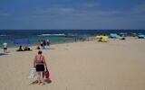 Des Israéliens et des touristes profitent de la plage de Césarée le 21 août 2023. (Crédit : Michael Giladi/Flash90)