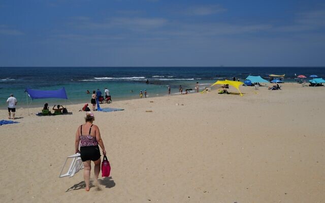Des Israéliens et des touristes profitent de la plage de Césarée le 21 août 2023. (Crédit : Michael Giladi/Flash90)