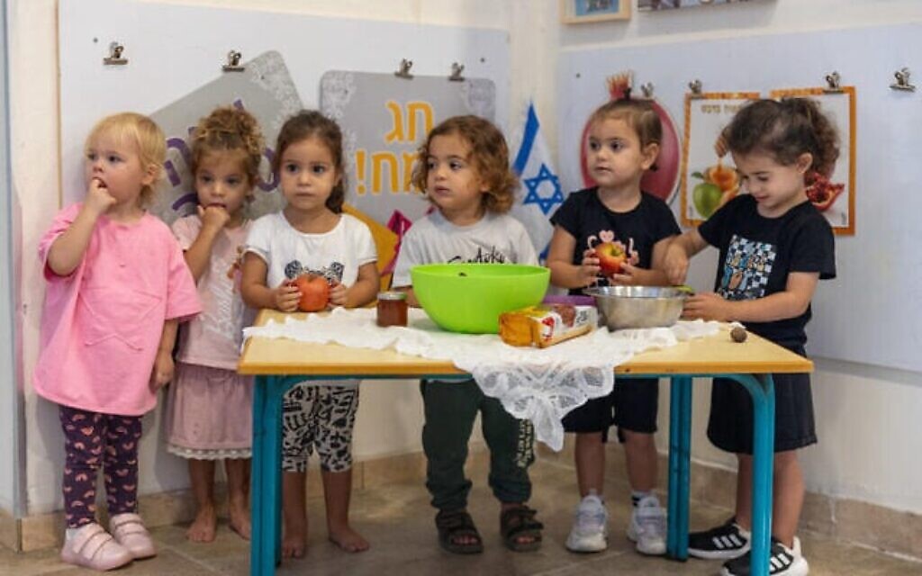 Des enfants juifs apprennent les coutumes de Rosh Hashana dans un jardin d'enfants à Moshav Yashresh, dans le centre d'Israël, le 1er octobre 2024. (Crédit : Yossi Aloni/Flash90)