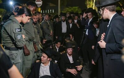 Des hommes haredim participent à un rassemblement contre l'emprisonnement d'étudiants juifs d'un séminaire qui n'ont pas respecté un ordre de recrutement de l'armée, devant la prison militaire de Beit Lid, près de Netanya, le 14 août 2025. (Crédit : Tal Gal/Flash90)