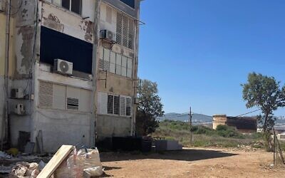 Un ancien réservoir de pétrole près d'un immeuble délabré de la rue Deganya à Kiryat Haim, dans le nord d'Israël, le 2 juillet 2025 (Crédit : Sue Surkes/Times of Israel)