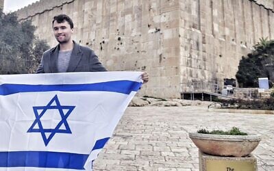 Charlie Kirk tenant un drapeau d'Israël devant le Tombeau des Patriarches, à Hébron, en Cisjordanie, sur une photo non datée. (Crédit : Itamar Ben Gvir/X via JTA)