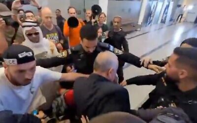 Des policiers entourent le député du Likud Eli Dallal après qu’il a été bousculé et est tombé à terre en traversant une foule de manifestants anti-gouvernementaux lors d’un événement du Likud à Kfar Saba, dans le centre d’Israël, le 20 septembre 2025. (Crédit : Capture d’écran/X ; utilisée conformément à la clause 27a de la loi sur le droit d’auteur)