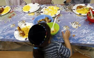 Un jeune garçon juif mange au centre Yad Ezra V'Shulamit à Jérusalem, qui sert chaque jour un repas chaud à plus de 1 200 enfants vivant sous le seuil de pauvreté. 27 septembre 2011. (Crédit : Uri Lenz/Flash90)