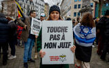 Un manifestant tient une pancarte sur laquelle on peut lire « Ne touchez pas à mon Juif » lors d'une marche contre l'antisémitisme, dans le cadre des manifestations nationales organisées par la Ligue belge contre l'antisémitisme, dans le centre de Bruxelles, le 10 décembre 2023. (Photo de Simon Wohlfahrt / AFP)
