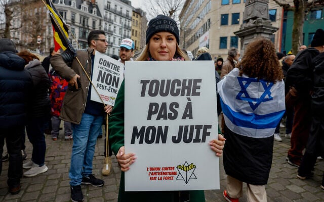 Un manifestant tient une pancarte sur laquelle on peut lire « Ne touchez pas à mon Juif » lors d'une marche contre l'antisémitisme, dans le cadre des manifestations nationales organisées par la Ligue belge contre l'antisémitisme, dans le centre de Bruxelles, le 10 décembre 2023. (Photo de Simon Wohlfahrt / AFP)