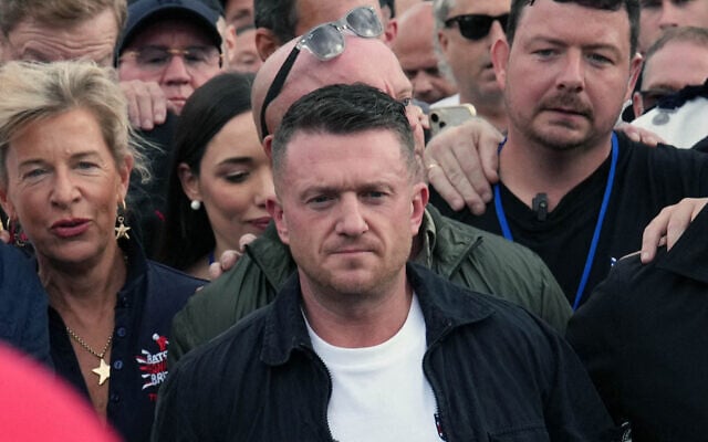 L'activiste britannique de droite dure et anti-islam Tommy Robinson, de son vrai nom Stephen Yaxley-Lennon, fait un geste alors qu'il défile avec des partisans, dont la commentatrice d'extrême droite Katie Hopkins (au fond à gauche), dans le centre de Londres lors d'une marche pour la « liberté d'expression », le 13 septembre 2025. (Crédit : Carlos Jasso/AFP)