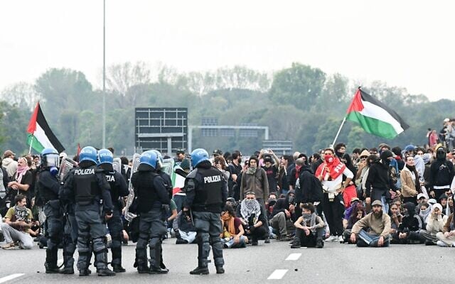 Des manifestants anti-Israël assis devant des policiers lors d'une manifestation contre l'interception par Israël de la flottille Global Sumud à destination de Gaza, sur une autoroute à Milan, en Italie, le 3 octobre 2025. (Crédit : Stefano Rellandini/AFP)