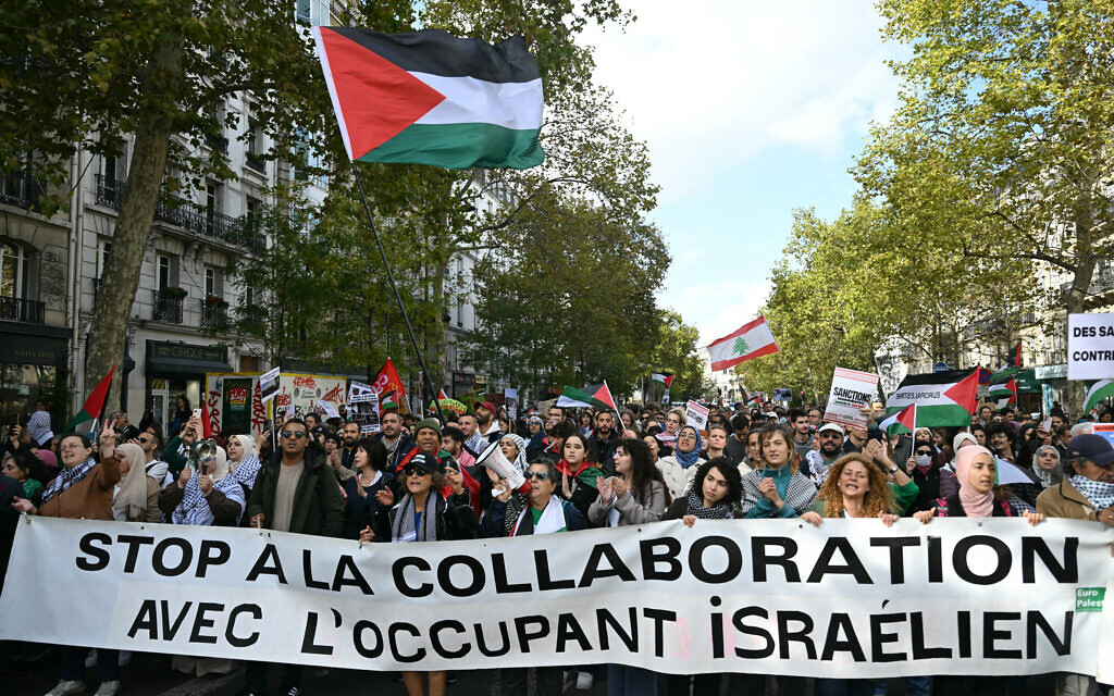 Des manifestants pro-palestiniens et anti-Israël brandissent une banderole sur laquelle est écrit « Stop à la collaboration avec l'occupant israélien » et des drapeaux palestiniens lors d'un rassemblement de solidarité avec les Palestiniens et pour protester contre l'interception par l'armée israélienne de la flottille Global Sumud, à Paris, le 4 octobre 2025. (Crédit : Anna KURTH / AFP)