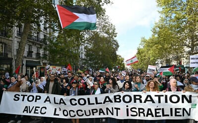 Des manifestants pro-palestiniens et anti-Israël brandissent une banderole sur laquelle est écrit « Stop à la collaboration avec l'occupant israélien » et des drapeaux palestiniens lors d'un rassemblement de solidarité avec les Palestiniens et pour protester contre l'interception par l'armée israélienne de la flottille Global Sumud, à Paris, le 4 octobre 2025. (Crédit : Anna KURTH / AFP)