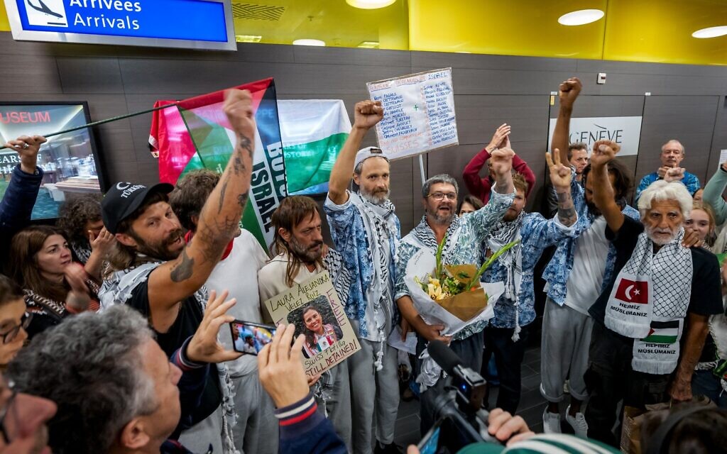 Des militants suisses, qui naviguaient à bord de navires de la flottille Global Sumud, lèvent le poing après avoir atterri à l'aéroport de Genève en provenance d'Istanbul, après qu'Israël a intercepté la flottille à destination de Gaza et arrêté des centaines de personnes, à Genève, le 5 octobre 2025. (Crédit : Fabrice COFFRINI / AFP)