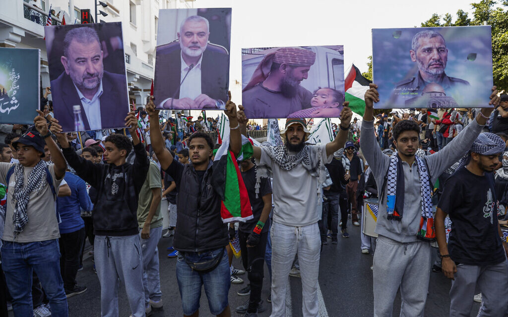 Des manifestants brandissent des drapeaux palestiniens et des pancartes représentant des portraits de chefs du groupe terroriste palestinien du Hamas - dont Salah Arouri (1er à g), Ismail Haniyeh (2e en partant de la gauche) et Mohammed Deif (4e en partant de la gauche), - lors d'une marche appelant à la fin de la guerre dans la bande de Gaza et protestant contre la normalisation des relations entre le Maroc et Israël, sur l'avenue Mohammed V à Rabat, le 5 octobre 2025. (Crédit : Abdel Majid BZIOUAT / AFP)