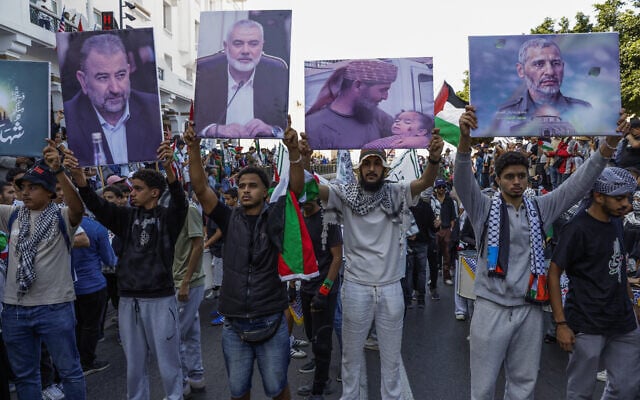 Des manifestants brandissent des drapeaux palestiniens et des pancartes représentant des portraits de chefs du groupe terroriste palestinien du Hamas - dont Salah Arouri (1er à g), Ismail Haniyeh (2e en partant de la gauche) et Mohammed Deif (4e en partant de la gauche), - lors d'une marche appelant à la fin de la guerre dans la bande de Gaza et protestant contre la normalisation des relations entre le Maroc et Israël, sur l'avenue Mohammed V à Rabat, le 5 octobre 2025. (Crédit : Abdel Majid BZIOUAT / AFP)